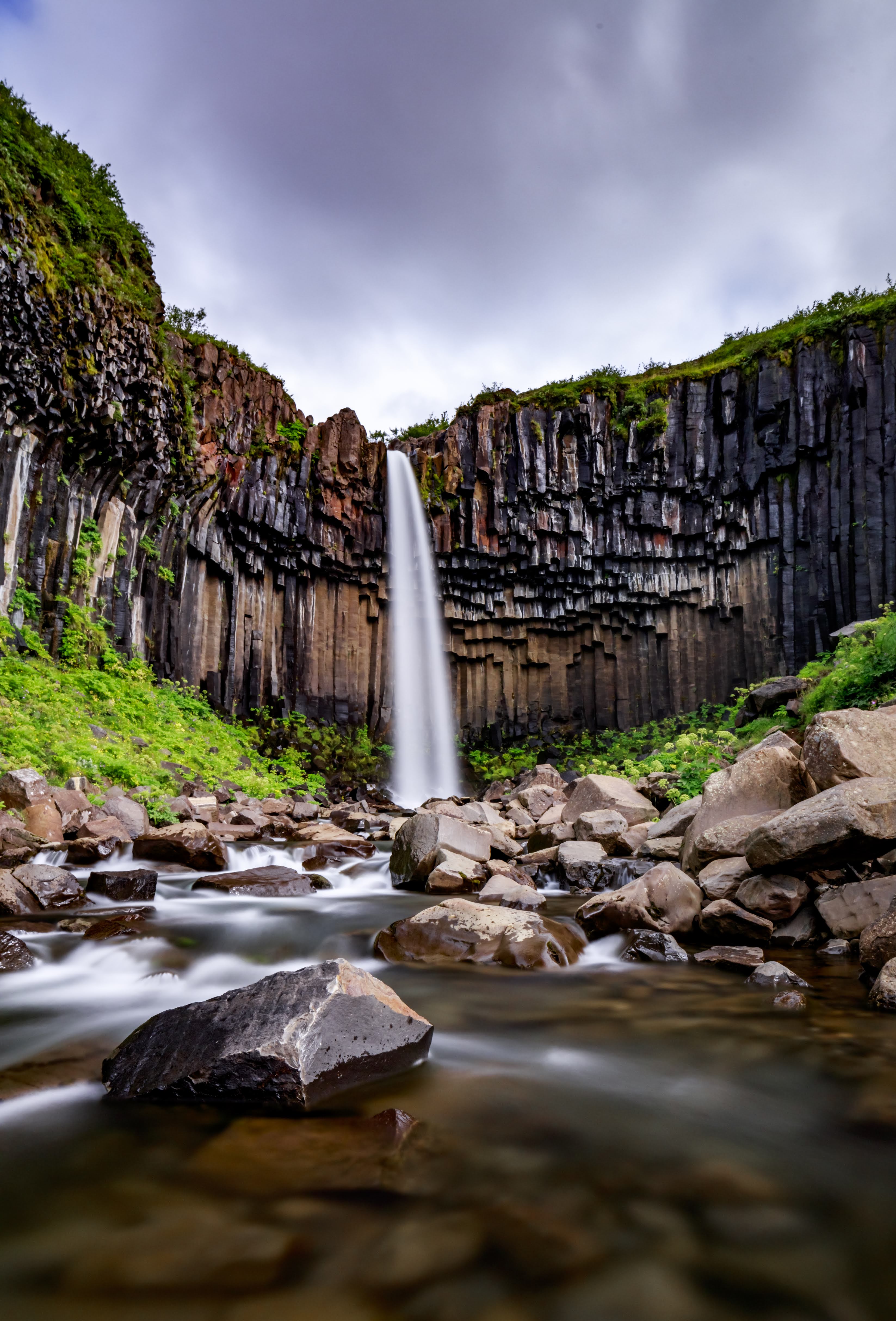 Waterfall cascading down a rocky cliff face with greenery