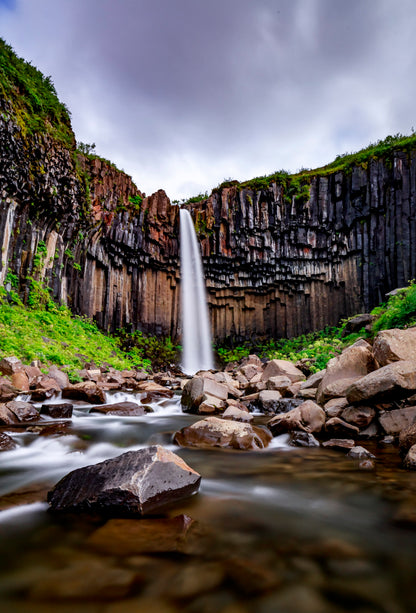 Waterfall cascading down a rocky cliff face with greenery